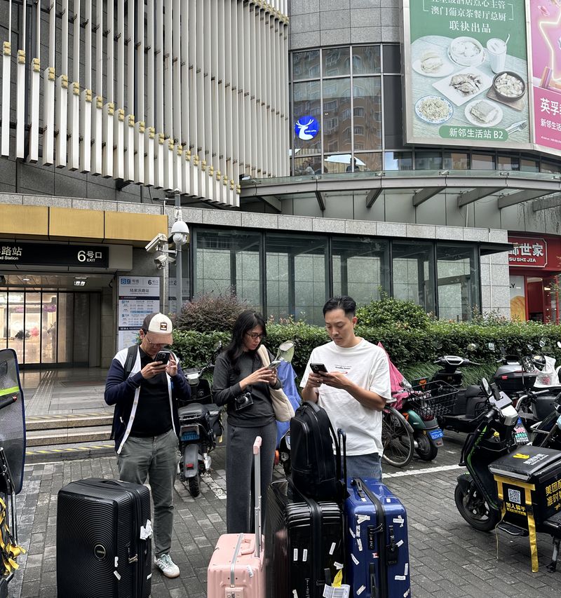 Đứng trên phố cầm điện thoại cạnh vali